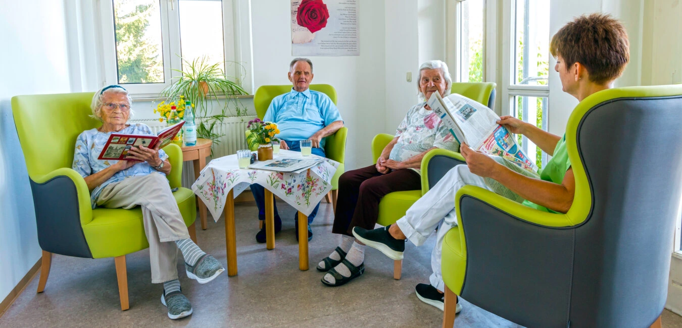 Tagespflege im „Haus Ölbaum“ mit der Zeitungsschau um die Besucher am täglichen Geschehen teilzuhaben.